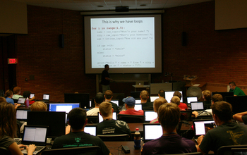 students in an auditorium looking projector screen